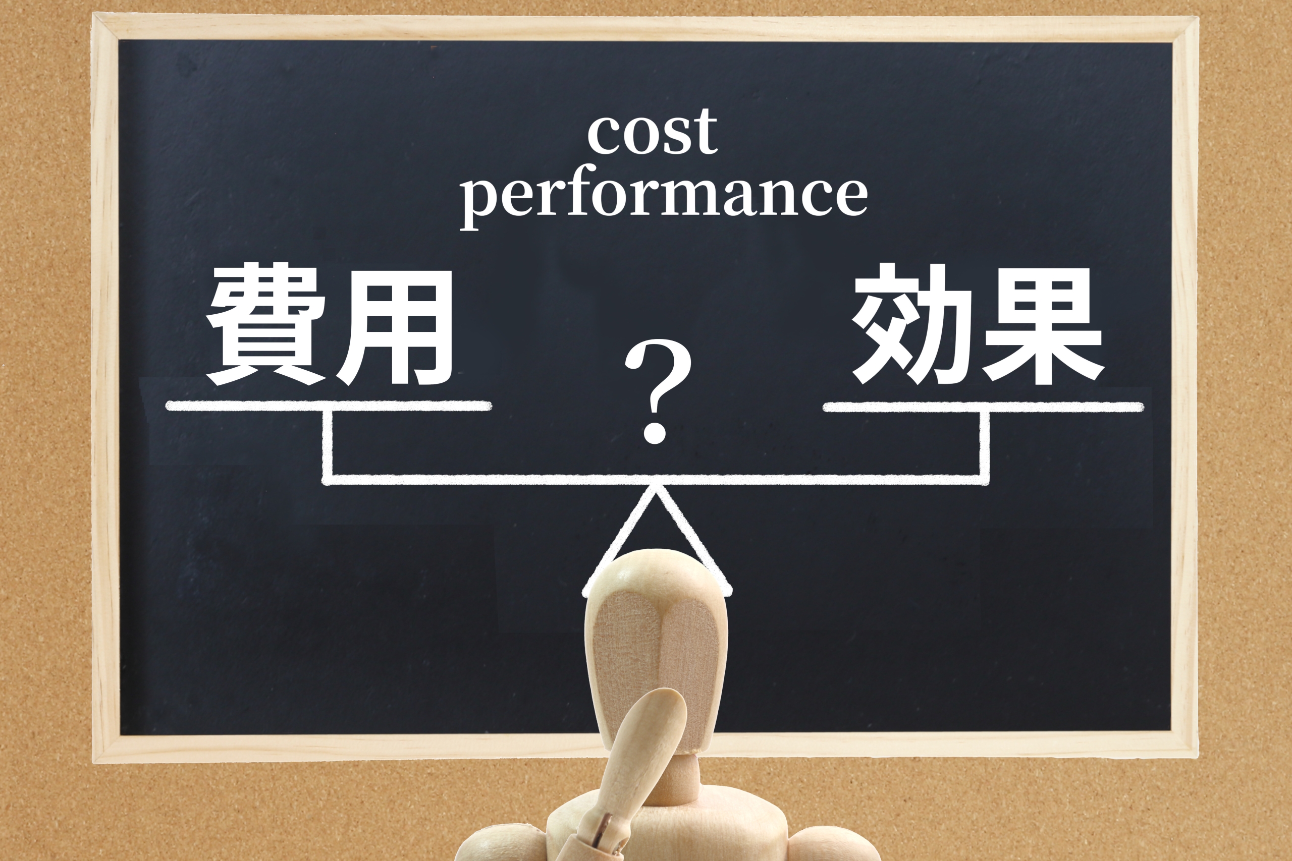 「費用」と「効果」の天秤を見つめる木製のマネキンと、黒板に描かれた「cost performance」の文字