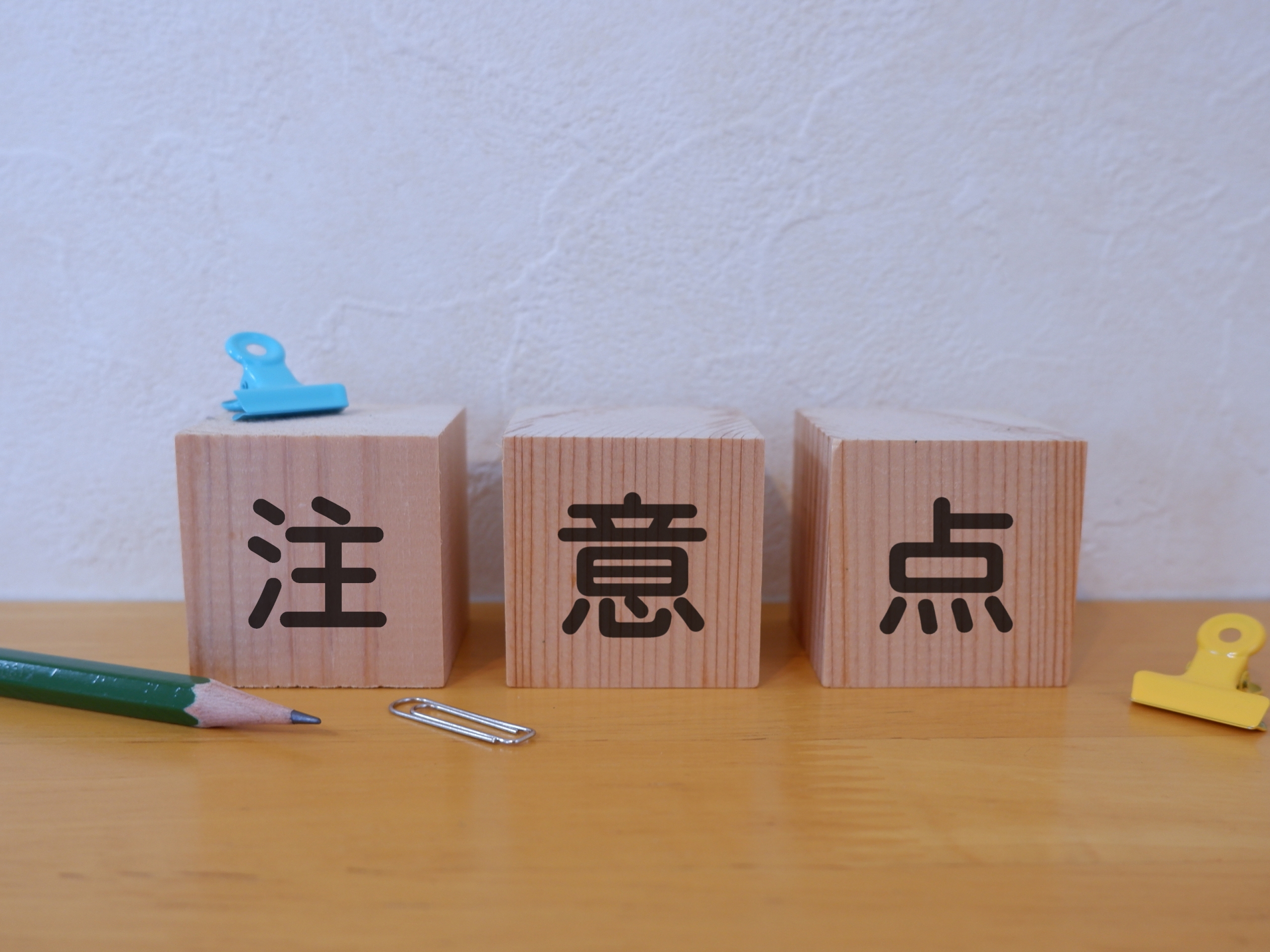 「注意点」と書かれた木製のキューブブロックと文房具